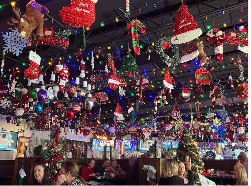 A restaurant ceiling completely packed with ornaments and twinkling lights above guests