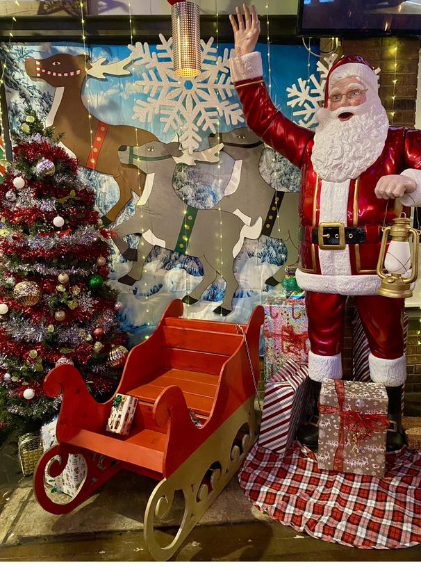 A jolly Santa figure beside a decorative sleigh display