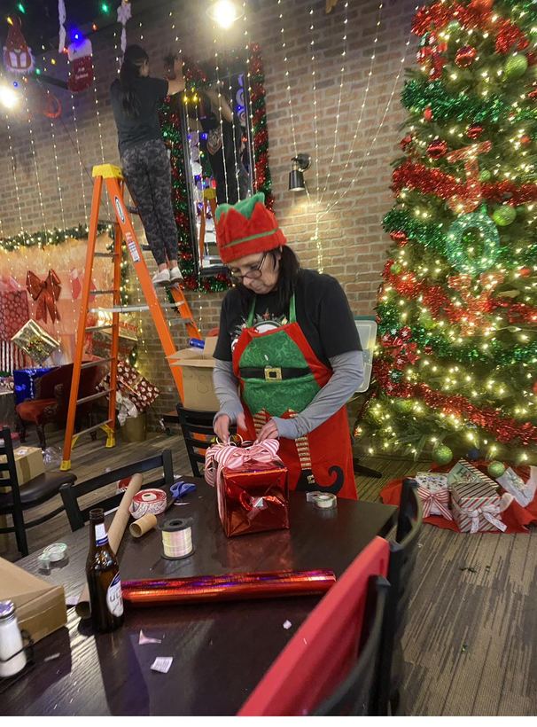 A festive host adding finishing touches by the tree