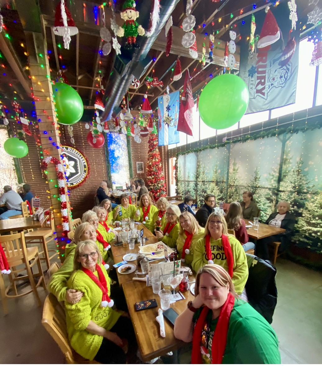 A group of friends in festive sweaters dining at a Jolly Elf holiday popup
